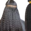 A close-up of a person's head shows Microlinks being applied in small sections. The extensions are attached near the roots with microbeads. The natural hair and extensions are long, straight, and dark. To the right, a bundle of the same type of Microlinks from Cosmetology Fairfax County is shown.